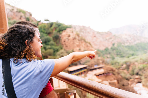 A woman embracing a man pointing to the horizon in front of an arid landscape