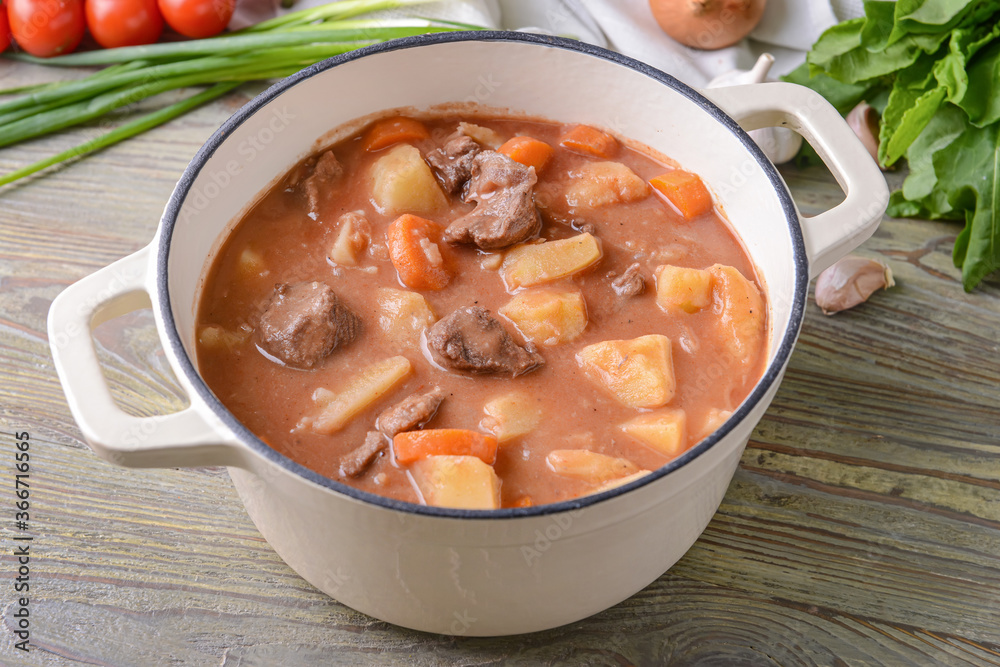 Pot with tasty beef stew on table