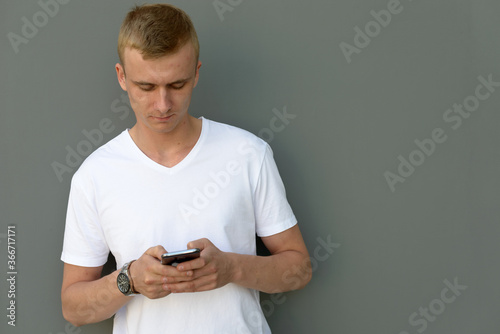 Portrait of young blond man against concrete wall outdoors