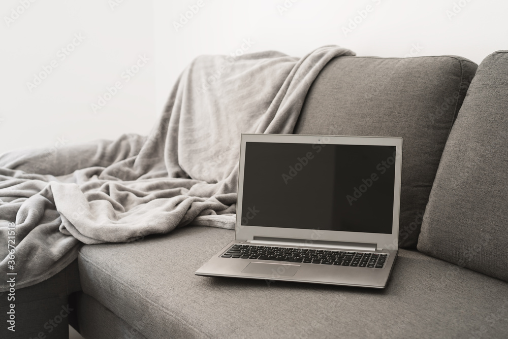Laptop computer on gray sofa. Work from home concept Laptop computer on gray sofa. Work from home concept
