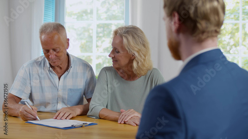 Happy senior couple sign document at meeting with financial advisor