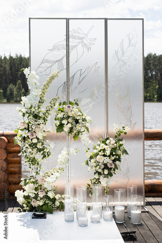 Vertical photo of wedding ceremony with white transparent screens and fresh white flowers and candles