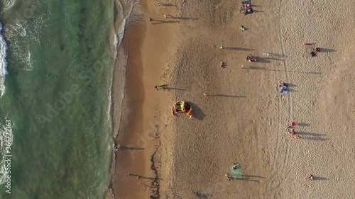 Sunset at the beach with people walking and Kite surfers enjoying last moments of Sun, Aerial view.
