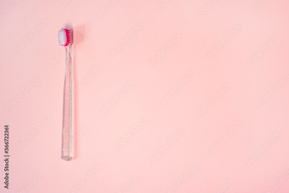 Pink and clear toothbrush with a toothpaste on a pastel pink background Pink and clear toothbrush with a toothpaste on a pastel pink background