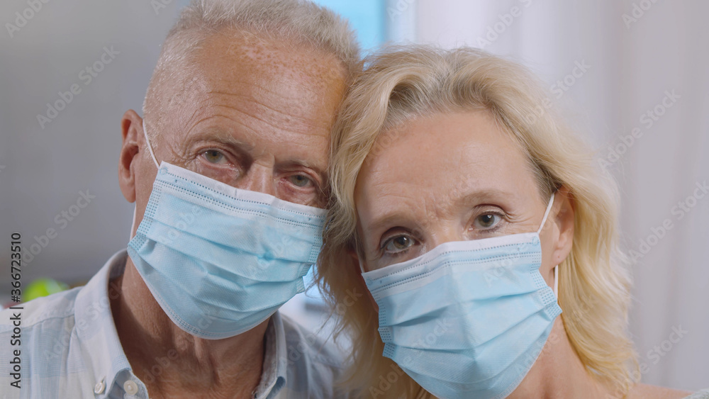 Close up of couple of elderly people in medical masks.
