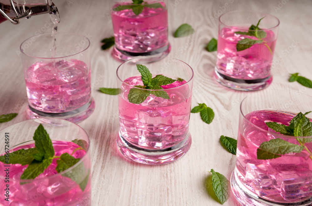 Glasses with pink drink, with ice and boil good on wooden table