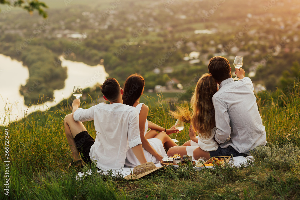 Group of young happy friends having picnic on the mountain.  - People have fun and celebrate during perfect sunny summer day. Friends interacting while having picnic on mountain on a sunny day.