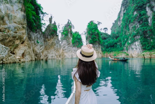 Beautiful asian woman standing on Long tail boat and take a picture with  Limenstone rocks at Cheow Lan lake in background, Ratchaprapha Dam, Khao Sok National Park in Thailand. photo