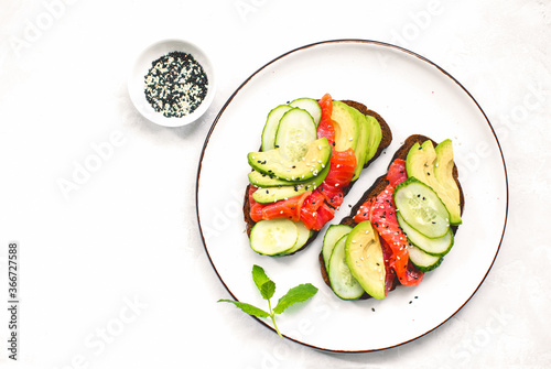 Avocado salmon toasts served on a dish, top down view