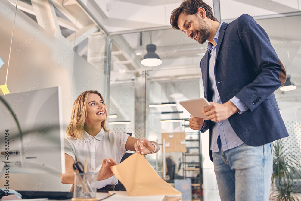 Obraz premium Cheerful young woman working with colleague in office