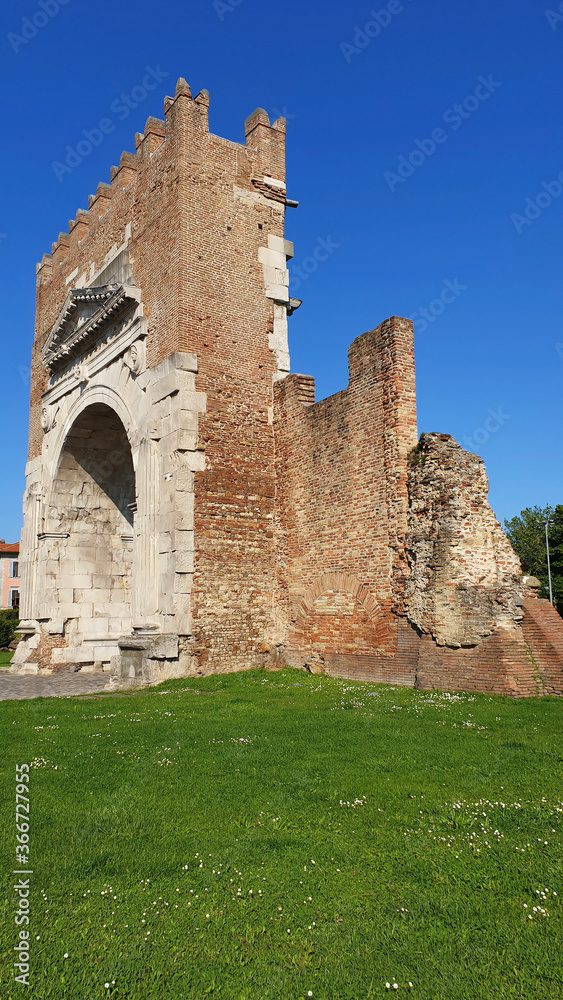 The Augustus arch is the main attraction of the city of Rimini. Triumphal arch of Rimini on a sunny summer day. Vertical.