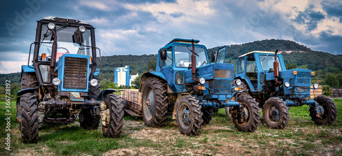 Dramatic view of three old farm tractors