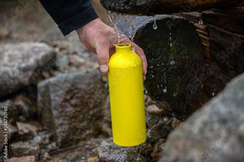 turysta napełniający żółtą metalowa butelkę wodą