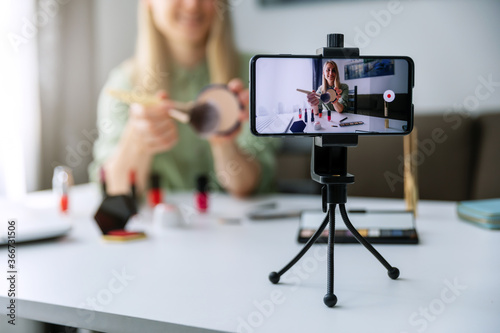 makeup blogger influencer recording tutorial video with phone for social media at home photo