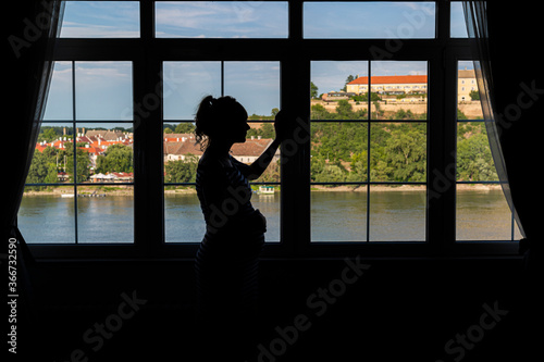 Silhouette of a pregnant woman by the window
