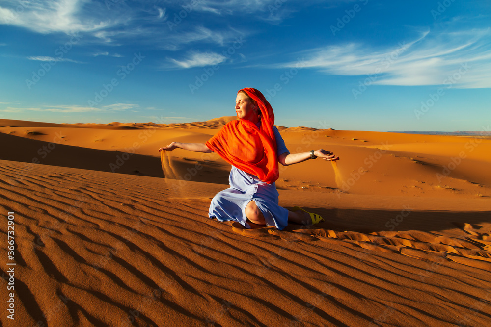 Girl plays with sand in the Sahara desert.