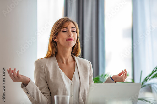 Fotografie Young woman practicing meditation at the office desk