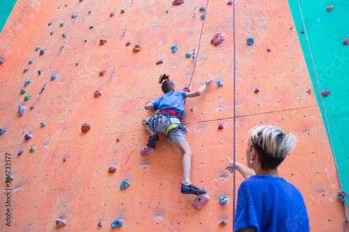 A boy climbs the wall, a coach teaches a child