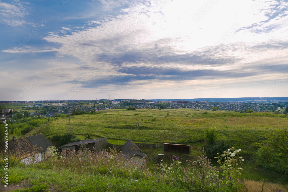 View from the hill to the city of Volkovysk, Belarus. Field, meadow, sky, village, abandoned buildings. Summer holidays in Belarus.