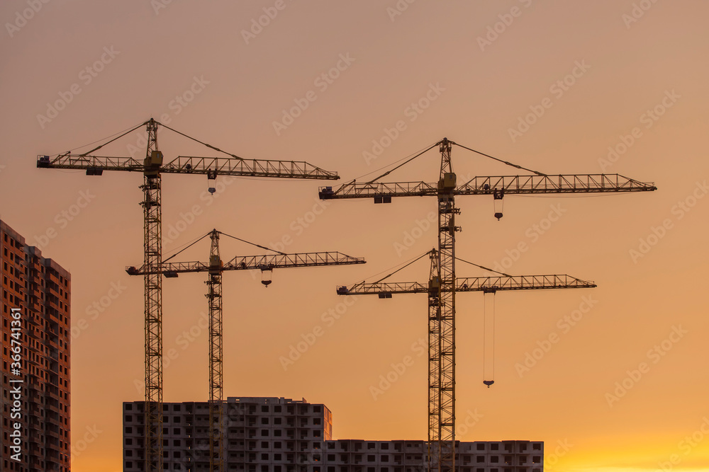 construction cranes against the background of bright evening clouds	
