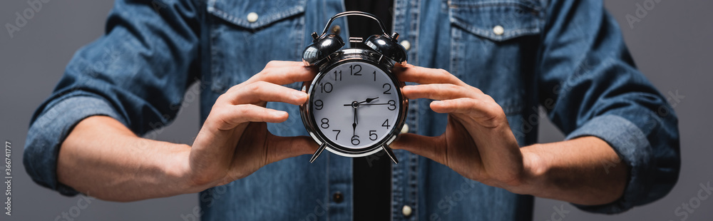 Panoramic crop of man holding alarm clock isolated on grey, concept of time management