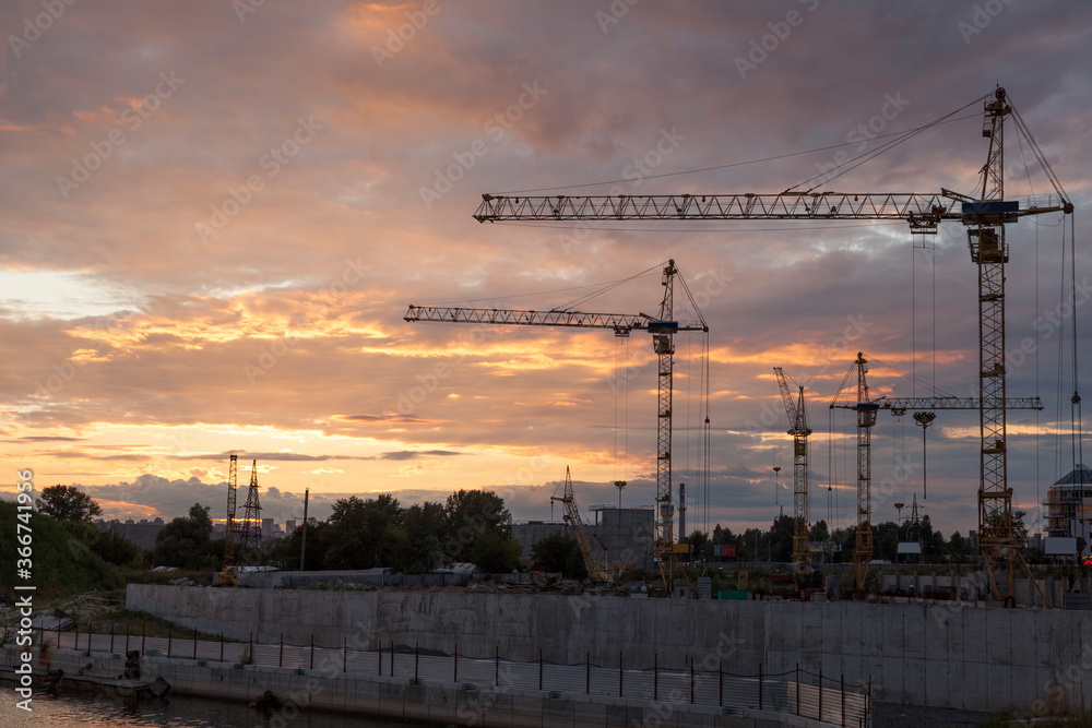 construction cranes against the background of bright evening clouds	
