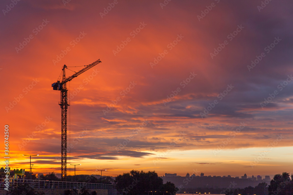 construction crane against the background of bright evening clouds	
