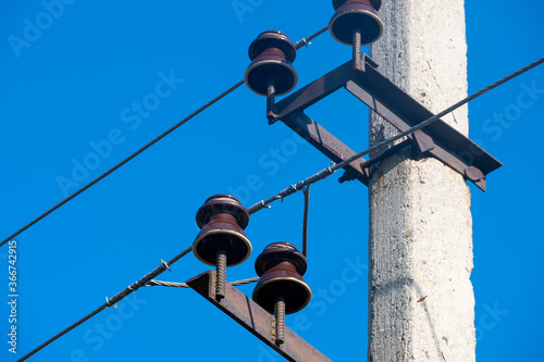 Closeup view of electric wires with electric insulator on a concrete pole photo