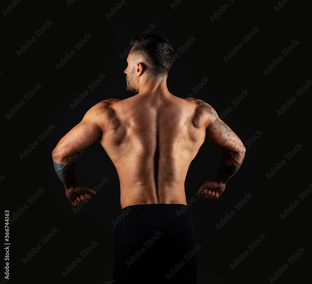 Strong man view back. Bodybuilder on black background.