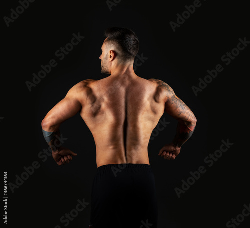 Strong man view back. Bodybuilder on black background.