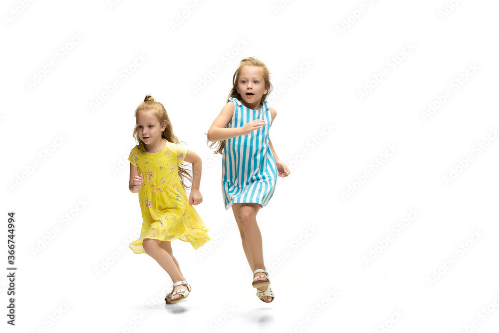 Happy children, little and emotional caucasian girls jumping and running isolated on white background. Looks happy, cheerful, sincere. Copyspace for ad. Childhood, education, happiness concept. Happy children, little and emotional caucasian girls jumping and running isolated on white background. Looks happy, cheerful, sincere. Copyspace for ad. Childhood, education, happiness concept.