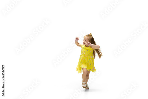 Happy child, little and emotional caucasian girl jumping and running isolated on white background. Looks happy, cheerful, sincere. Copyspace for ad. Childhood, education, happiness concept.