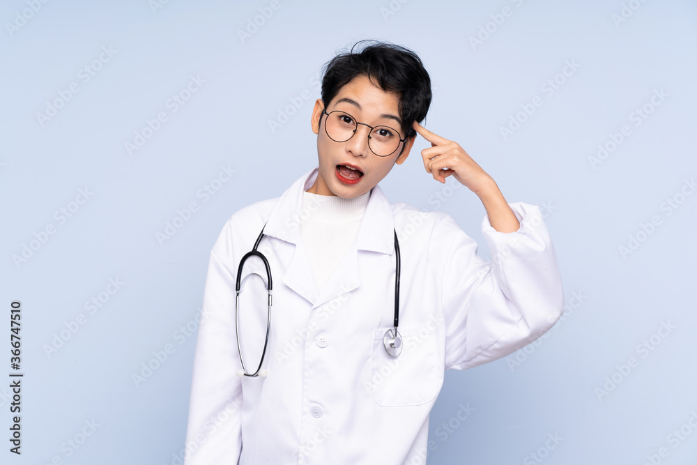 Doctor Asian woman over isolated blue background intending to realizes the solution