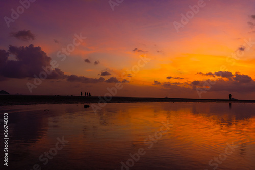 Burning bright sky during sunset on a tropical beach. Sunset during the exodus  the strength of people walking on water