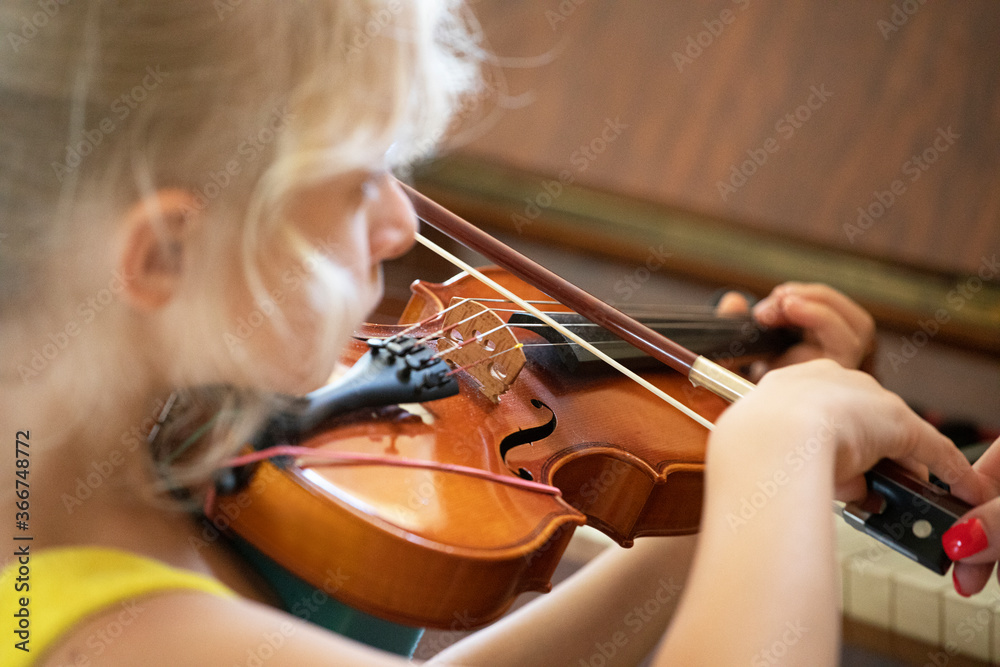 little girl with concentration plays on a small violin, suzuki lessons, learn flattens hand horizontal shape, music lesson little girl with concentration plays on a small violin, suzuki lessons, learn flattens hand horizontal shape, music lesson