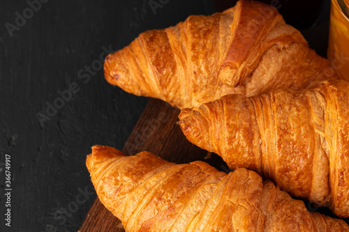 Fresh croissants on wooden board close up