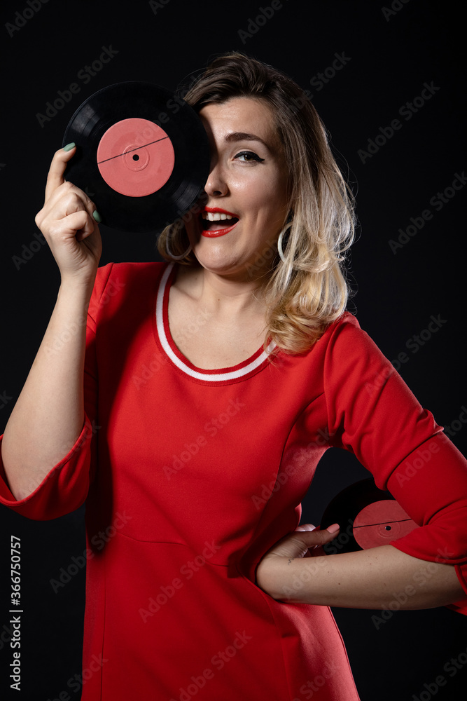 Fototapeta premium funny blonde girl with vinyl records in hands on a black background