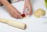 Woman wraps cherries in dough. Cooking dumplings.