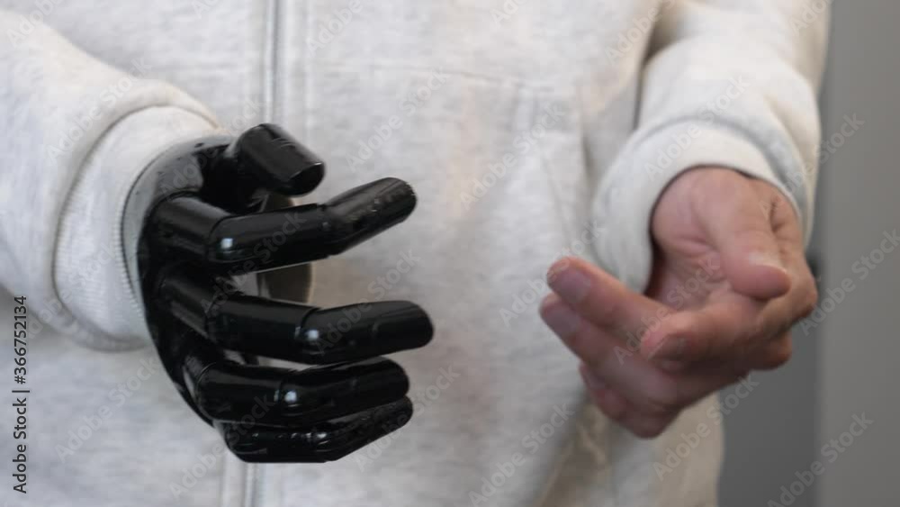 Young men with an artificial arm making hands gestures while he is speaking. Handicap person working with a fake limb. Closeup shot. Young men with an artificial arm making hands gestures while he is speaking. Handicap person working with a fake limb. Closeup shot.