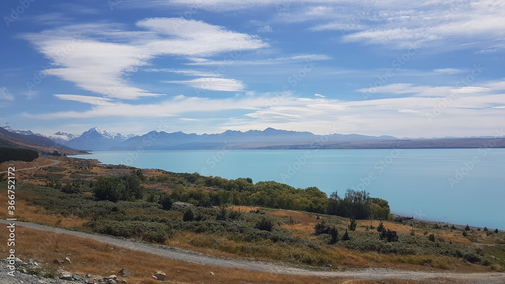 Fototapeta premium Lake Pukaki with mountain, white clouds, blue lake and sky in summer, the largest of three parallel alpine lakes running north–south along the edge of the Mackenzie Basin, South Island, New Zealand