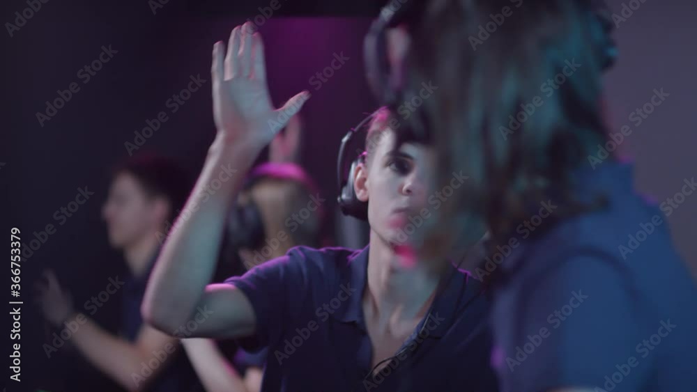 Modern team of gen Z people taking part in modern online cybersport competition successfully winning it and doing high five