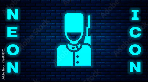 Obraz na plátně Glowing neon British guardsman with bearskin hat marching icon isolated on brick wall background