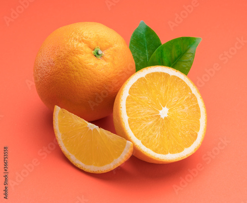 Orange fruit with orange slices and leaves isolated on orange background.