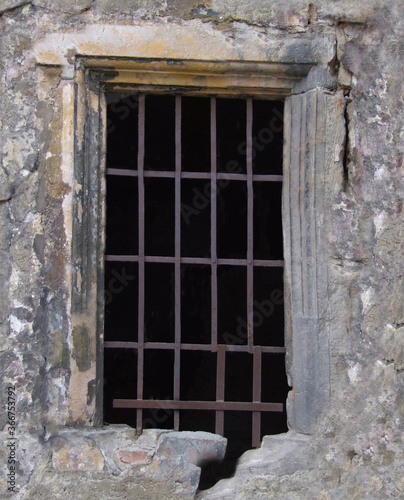 An old window with a metal grille of a historical building .Background or texture