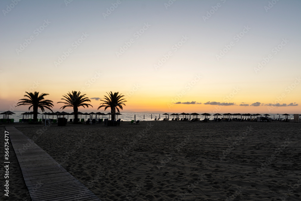 Obraz premium Sunrise with sand and palm trees