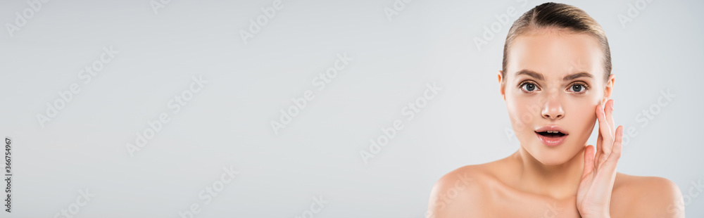 horizontal image of surprised and naked woman touching face isolated on grey