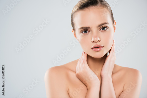 naked woman looking at camera and touching neck isolated on grey