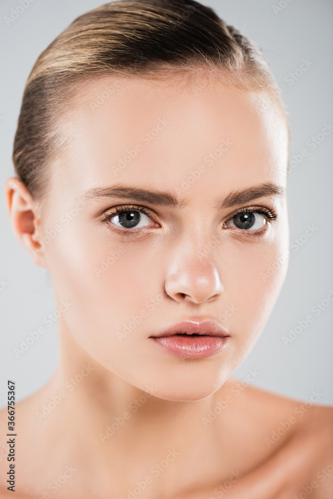 close up of naked young woman looking at camera isolated on grey