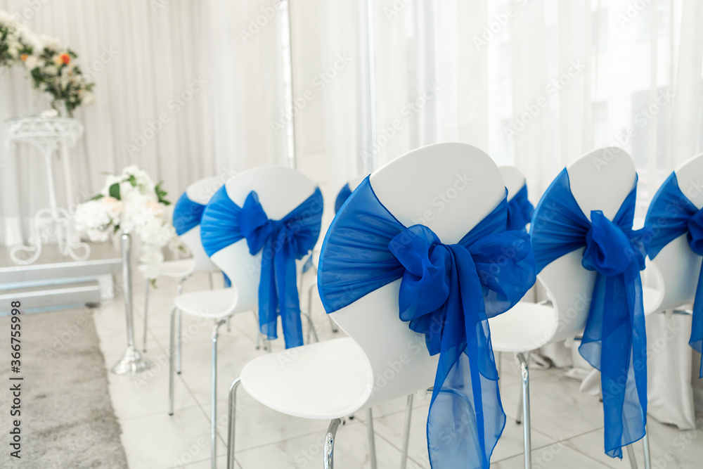 Bright room for weddings. Rows of guest chairs decorated with blue cloth Bright room for weddings. Rows of guest chairs decorated with blue cloth
