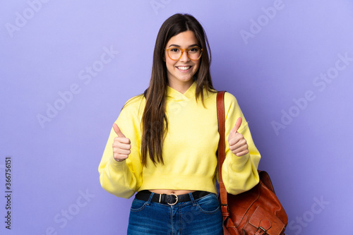 Teenager Brazilian student girl over isolated purple background giving a thumbs up gesture